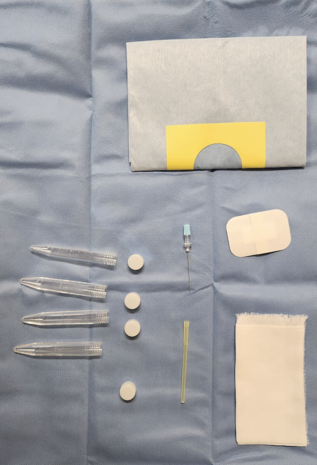 髄液検査に必要な物品の画像.穴あきの覆布,穿刺針,スピッツ4本,ガーゼ,サージカルバンテージが滅菌布の上に準備されている.